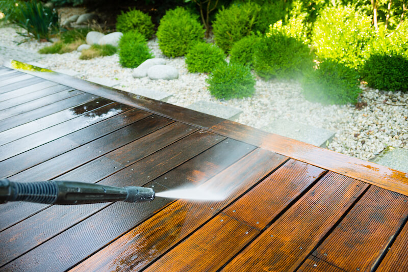 Picture of a patio deck and someone power washing it.